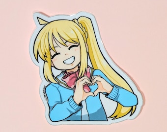 May include: A sticker featuring an anime-style character with blonde hair in a ponytail, wearing a blue jacket and pink scarf. The character is smiling and making a heart shape with their hands. The sticker has a white border and the text "KITTYCORIAN" is visible.