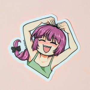 Puede incluir: Una pegatina con un personaje de estilo anime con pelo morado y un top verde. El personaje sonríe con los brazos por encima de la cabeza, formando un corazón. La pegatina tiene un borde blanco y el texto "KittyGorian" es visible.