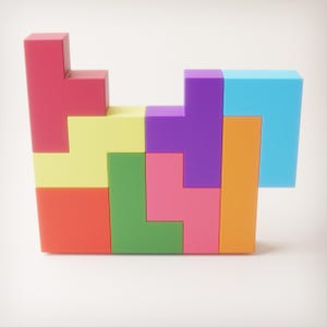 May include: A colorful Tetris-style puzzle composed of various geometric shapes. The puzzle features vibrant blocks in red, yellow, green, pink, orange, purple, and blue. The blocks are arranged in a partially completed structure, showcasing the game's iconic design.