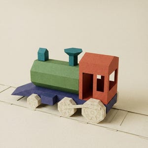 May include: A paper craft train model featuring a green cylindrical boiler, a red cab with open windows, and a dark blue base. The train has light beige wheels with a geometric spoke pattern and sits on a flat paper track with rectangular ties.