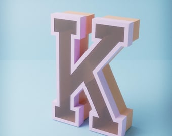 May include: A large, three-dimensional letter "K" in a stylized font. The letter has a light pink outline with a tan interior and a light blue background. The letter is angled slightly to the right.