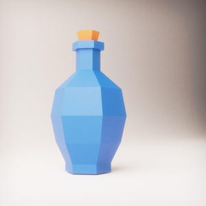 Puede incluir: Una botella geométrica azul claro con un tapón naranja. La botella tiene un diseño facetado, lo que le da una apariencia moderna y angular. El fondo es un degradado suave de blanco a marrón claro.