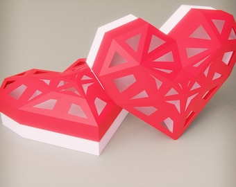 May include: A red and white paper heart shaped box with a geometric design. The box is made of paper and has a delicate, intricate design.