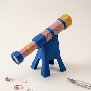 May include: A papercraft telescope model featuring a pink body with a marbled texture, accented by blue structural bands and a yellow eyepiece decorated with white constellation patterns, mounted on a sturdy blue paper tripod stand.