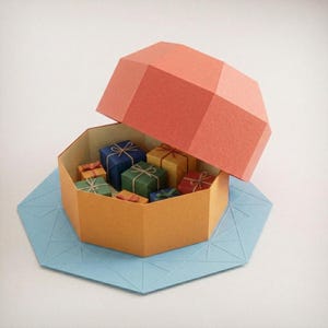 May include: A geometric paper box with a coral-colored lid, containing several miniature gift boxes in blue, yellow, green, and red, each tied with thin string. The entire structure rests on a light blue octagonal base with embossed lines.