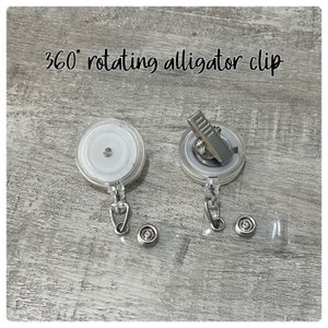 May include: Two clear, round badge reel clips with silver alligator clips. The text "360&deg; rotating alligator clip" is above the reels. Each reel has a metal snap and a clear plastic strap.