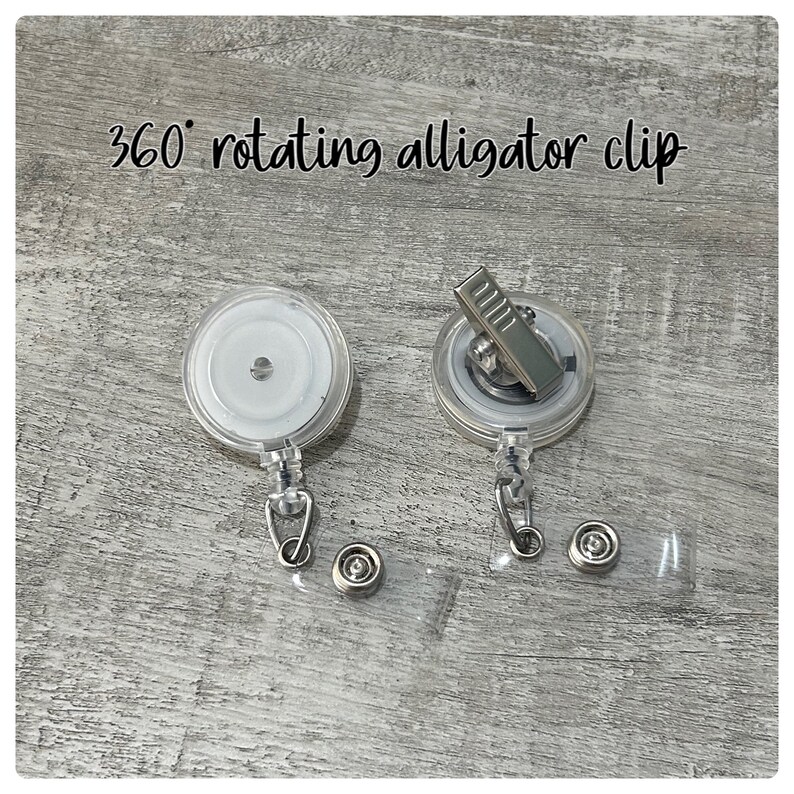 May include: Two clear, round badge reel clips with silver alligator clips. The text "360&deg; rotating alligator clip" is above the reels. Each reel has a metal snap and a clear plastic strap.