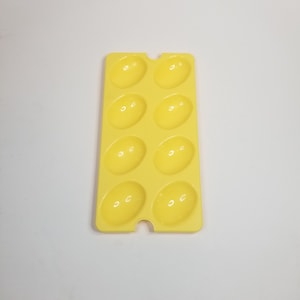 May include: Yellow plastic egg-shaped mold with eight individual compartments for making deviled eggs.