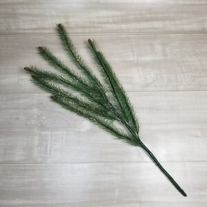 May include: A green artificial pine sprig with glitter, perfect for adding a touch of winter to your holiday decor.