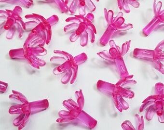 May include: A collection of pink plastic Christmas tree toppers with a flower design. The toppers have a pointed base and a flower-shaped top with multiple petals.