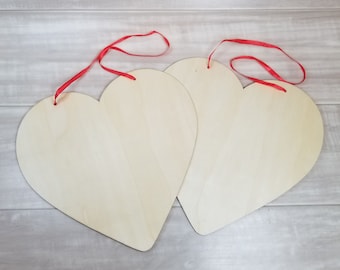 May include: Two unfinished wooden heart-shaped signs with red ribbon attached for hanging.