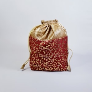 May include: A red drawstring bag with a gold floral pattern and a gold top.