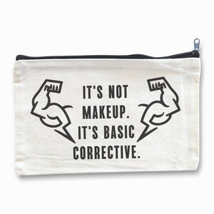 Könnte beinhalten: Weiße Canvas-Kosmetiktasche mit schwarzem Besatz und einer schwarzen Grafik von zwei Bizepsmuskeln mit dem Text "Es ist nicht Make-up. Es ist grundlegende Korrektur."