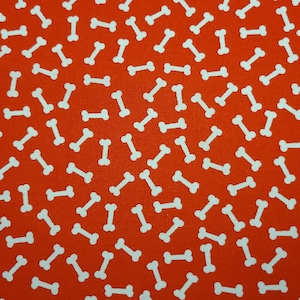 May include: Red fabric with a white bone pattern. The bones are scattered randomly across the fabric.