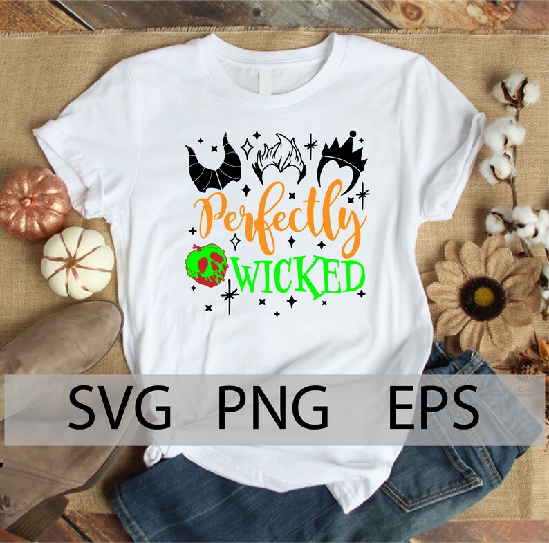 K&ouml;nnte beinhalten: Wei&szlig;es T-Shirt mit einem schwarzen und gr&uuml;nen Design, auf dem "Perfectly Wicked" mit einem gr&uuml;nen Apfel und schwarzen Silhouetten von Kronen und H&ouml;rnern steht.