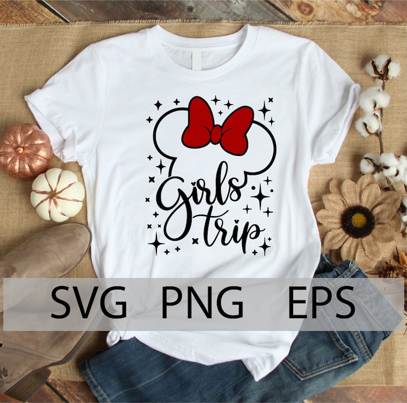 May include: White t-shirt with a black and red graphic design. The graphic features a Mickey Mouse ear silhouette with a red bow and the text "Girls Trip" with black glitter stars.