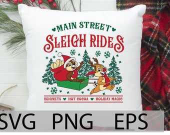 May include: White pillow with a red and green design featuring Chip and Dale riding a sleigh. The text "Main Street Sleigh Rides" is in a red, white, and green font. The text "Beignets, Hot Cocoa, Holiday Magic" is at the bottom of the pillow.