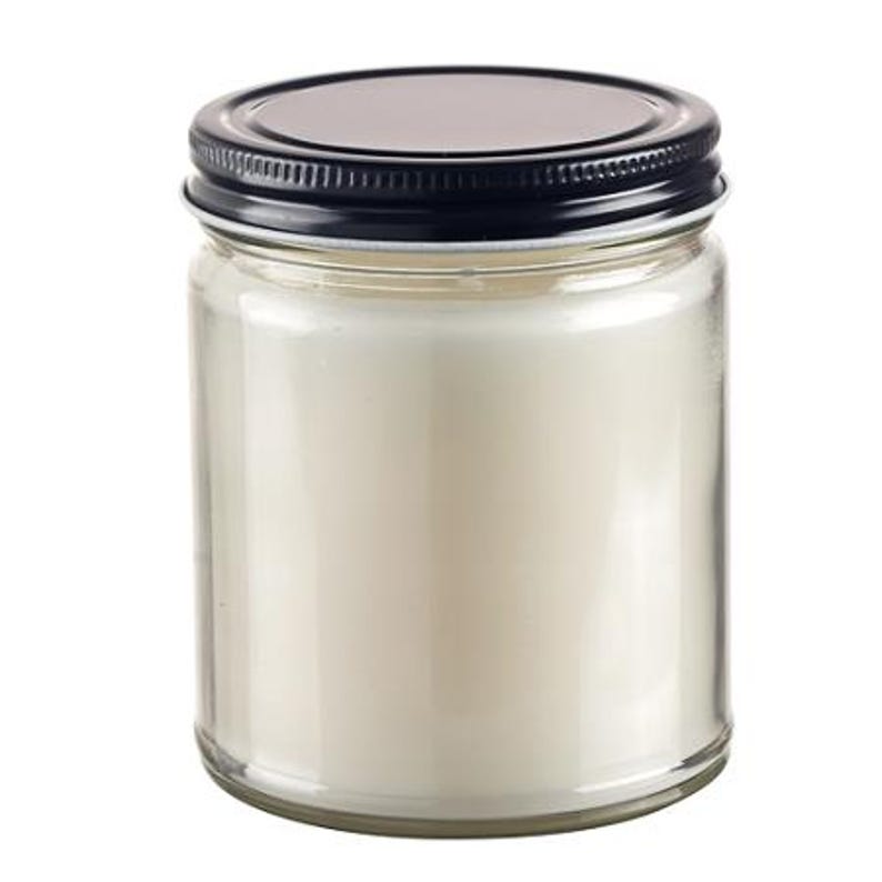 May include: A clear glass jar candle with a black lid. The candle inside is a creamy white color. The jar is cylindrical and has a simple, clean design, suitable for home decor.