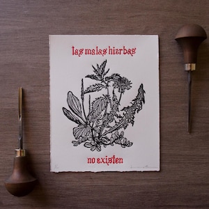May include: A rectangular white paper print featuring a black ink botanical illustration of various weeds and the red text "las malas hierbas" above and "no existen" below, flanked by two wooden-handled metal carving tools on each side.