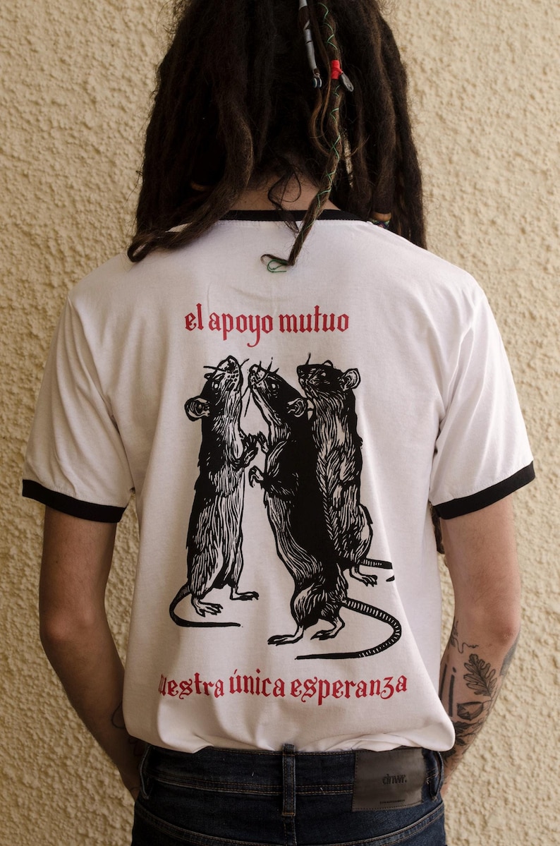 May include: White t-shirt with black trim and a graphic of three rats with the text "el apoyo mutuo nuestra &uacute;nica esperanza" in red.