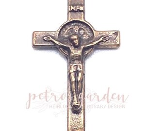 May include: A bronze crucifix with a figure of Jesus Christ on the cross. The crucifix has a circular halo around the head of Jesus and the letters "INRI" above the cross.