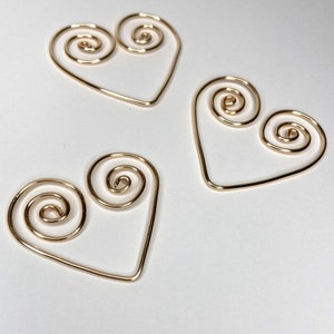 May include: Three gold wire heart-shaped ornaments with a spiral design.