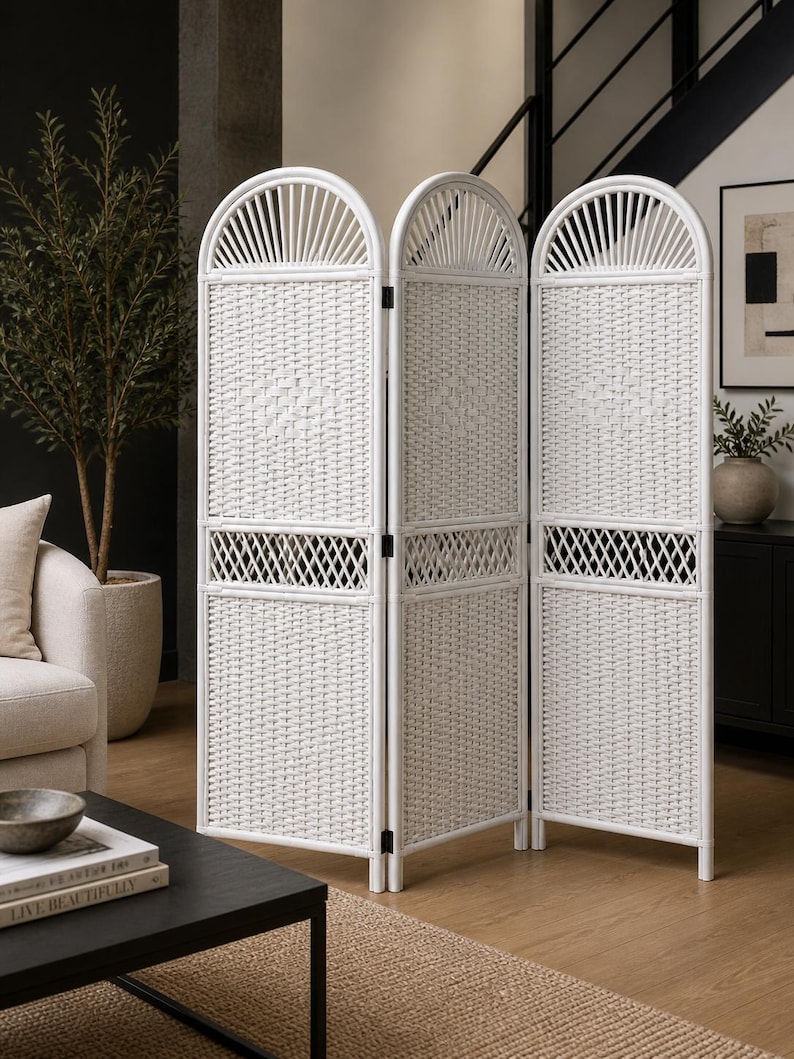 Puede incluir: Un biombo blanco de tres paneles. Cada panel tiene un dise&ntilde;o tejido con una parte superior arqueada decorativa. El separador est&aacute; hecho de un material de color claro y est&aacute; ubicado en una habitaci&oacute;n con una paleta de colores neutros.