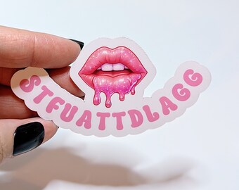 Op de afbeelding: Roze sticker met een druppelend, glitterend, roze lippenontwerp en de tekst "STFUATTDLAGG".