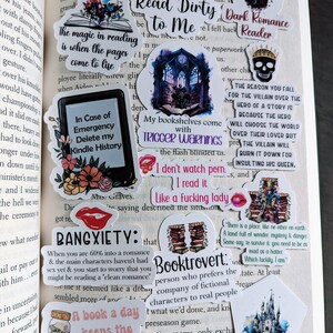 May include: A collection of colorful stickers with various book-themed quotes and illustrations. The stickers feature a dark gothic castle, a skull with a crown, a stack of books, a red lips sticker, a jar of medicine, and a castle with a fairytale theme. The stickers are perfect for decorating journals, laptops, or water bottles.