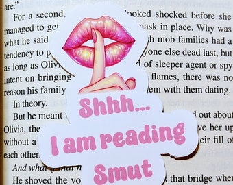 May include: Pink lips with a finger over them, a white sticker with the text "Shh... I am reading Smut" in pink letters.