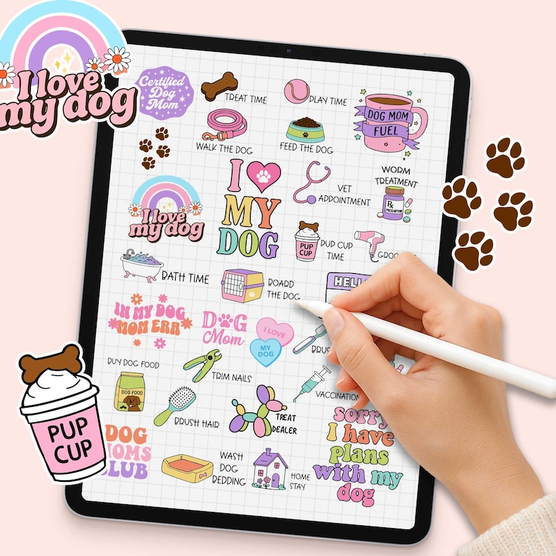 May include: A digital illustration on a tablet featuring dog-themed stickers. The stickers include phrases like "I love my dog," "Dog Mom," and various dog-related icons such as paw prints, a dog house, and a bone. A hand holding a stylus is also visible.
