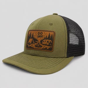 May include: An olive green baseball cap with a black mesh back and a rectangular brown patch on the front. The patch features a black graphic illustration of a tent, a campfire, and a camper with the text GO AWAY printed above the campfire.
