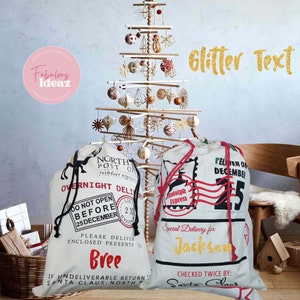 May include: Two white canvas Santa sacks with red and black trim. One sack says "OVERNIGHT DELIVERY" and "DO NOT OPEN BEFORE 25 DECEMBER" with the name "Bree" in gold glitter. The other sack says "DELIVER ON DECEMBER 25" with the name "Jackson" in gold glitter. Both sacks have a reindeer and a red stamp that says "Rudolph Express".