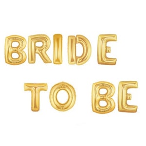 May include: Gold foil letter balloons spelling out "BRIDE TO BE".