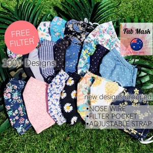 Op de afbeelding: Een verzameling stoffen gezichtsmaskers in verschillende patronen en kleuren, waaronder bloemen, paisley en stippen. De afbeelding bevat tekst met de tekst "FREE FILTER", "100+ Designs" en "new designs dropped". Kenmerken zijn neusdraad, filterzak en verstelbare band.