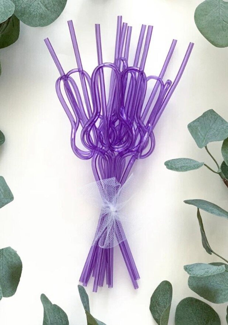 May include: A bunch of purple plastic drinking straws tied together with a white ribbon. The straws are bent into a heart shape.