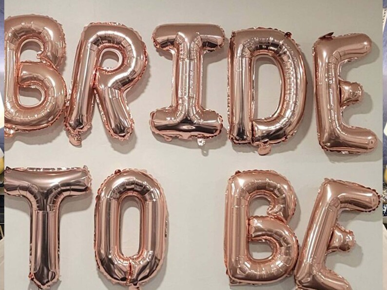 May include: Rose gold foil letter balloons spelling "BRIDE TO BE".
