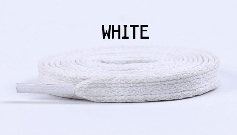 May include: White cotton shoelaces, rolled up and ready to be used. The laces are flat and have a woven texture.