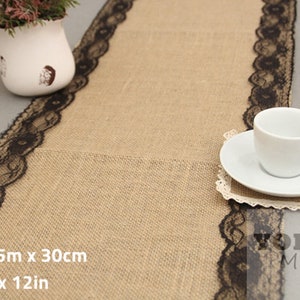 May include: A burlap table runner with black lace trim. The runner is 9 feet long and 12 inches wide. 2.75m x 30cm.