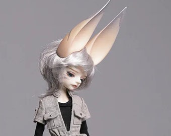May include: A fantasy doll with large, stylized ears and silver hair. The doll wears a gray vest over a black shirt and a matching skirt with pockets. The doll has pale skin and blue eyes, set against a gray background.
