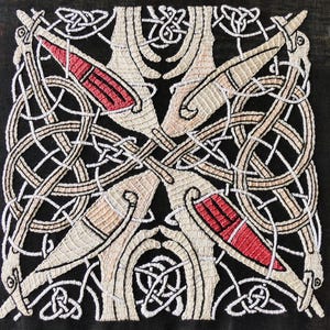 Pode incluir: Um tecido preto com um desenho de nó celta bordado em branco e vermelho. O desenho apresenta padrões intrincados entrelaçados e figuras de animais estilizadas.