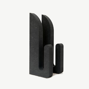 Puede incluir: Escultura de pared geom&eacute;trica abstracta negra con un dise&ntilde;o moderno. La escultura est&aacute; hecha de un material texturizado y tiene una forma tridimensional.