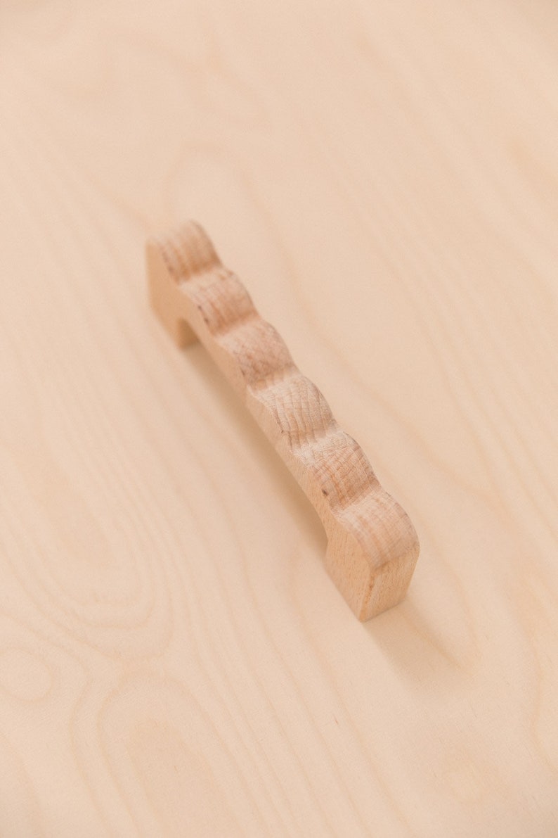 Puede incluir: Un pomo de madera para armario con un borde decorativo festoneado. El pomo es de color marr&oacute;n claro y tiene un dise&ntilde;o simple y elegante.