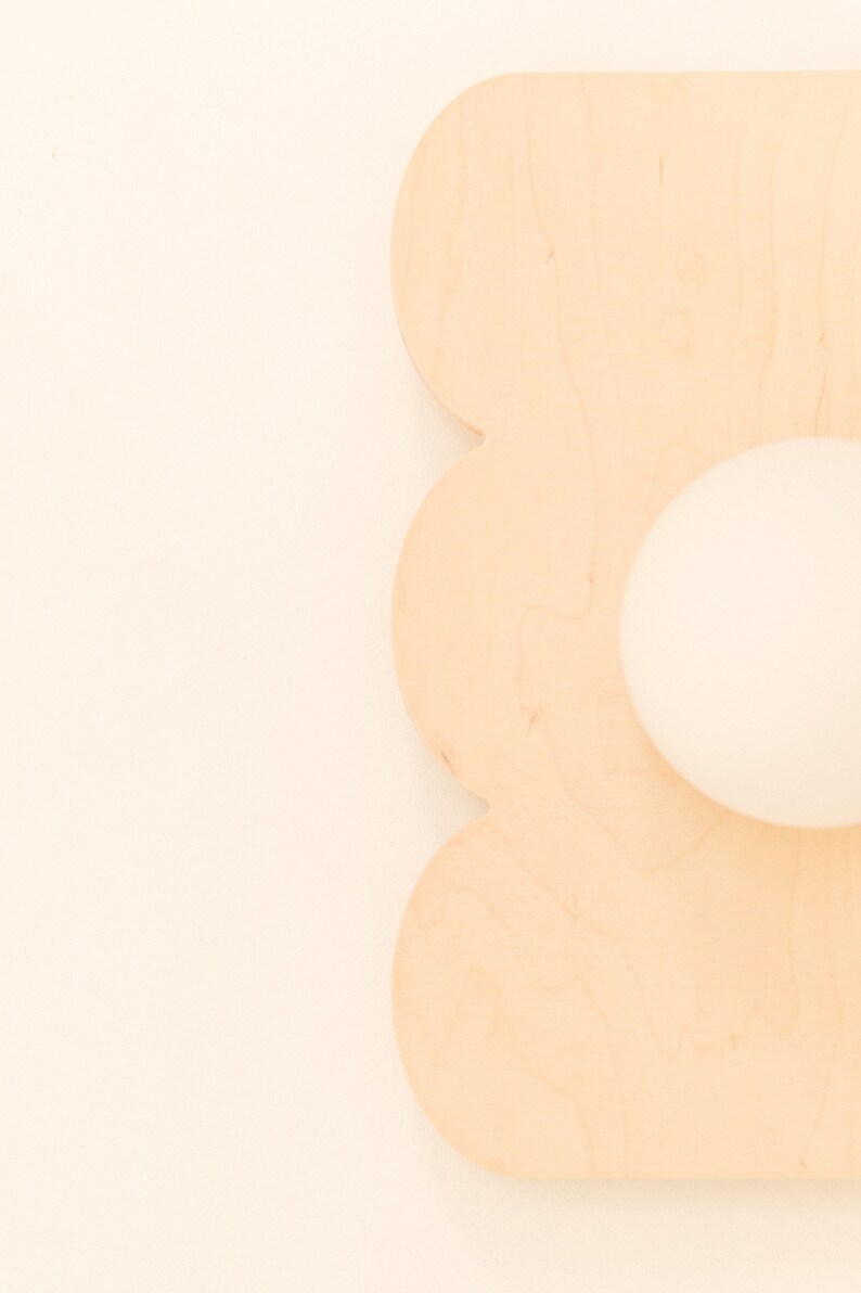 May include: A light brown wooden cutout of a flower with a round hole in the center.