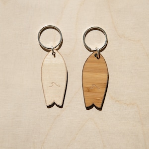 Wooden surfboard keychain with wave pattern