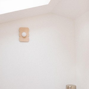 Wooden wall light with curved hourglass shape and glass globe