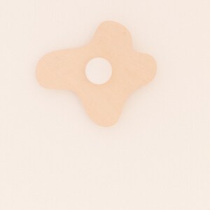 Pu&ograve; includere: Un decoro da parete di forma irregolare rosa chiaro con un cerchio bianco al centro. Il decoro &egrave; montato su una parete bianca.