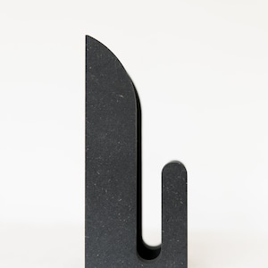 Puede incluir: Un gancho de pared negro, independiente, con la parte superior redondeada y un solo gancho.