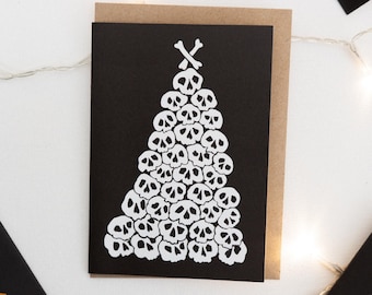May include: A black card with a white skull Christmas tree design. The tree is made up of many skulls stacked on top of each other, with two crossed bones at the top.