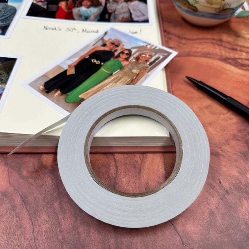 A roll of double-sided tape rests on an open photo album.